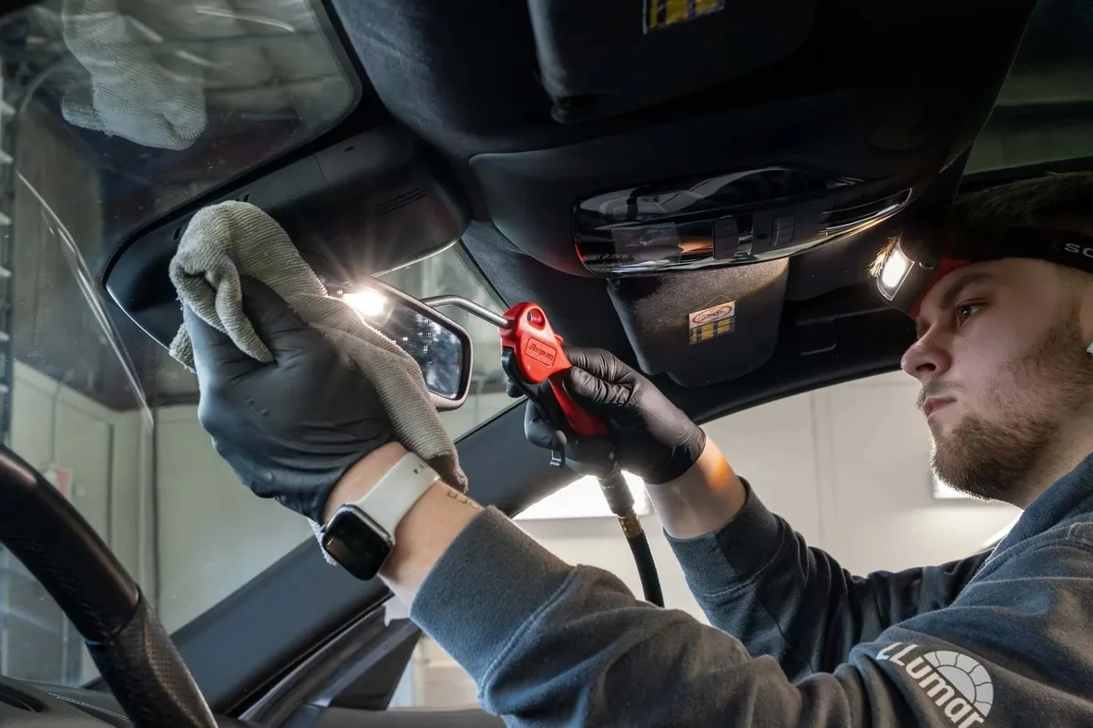 Detailer working inside a vehicle cabin